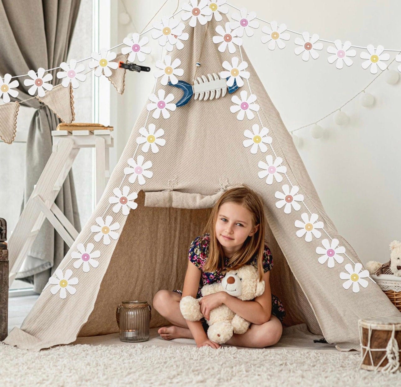 white daisy garland hanging over girl sitting in a tee pee